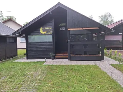 a black building with a large door in a yard at Spa Cottage the Moon house Terme Čatež in Čatež ob Savi