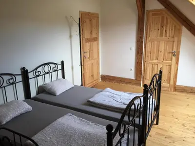 two twin beds in a room with a wooden floor at Hiša 1907 in Bled
