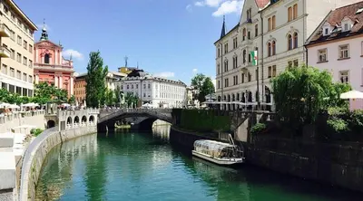 a boat on a river in a city with buildings at Lux room & ljubljana in Ljubljana