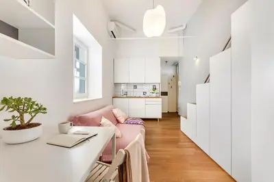 a living room with a pink couch and a table at Modern studio apartment in the heart of old city in Ljubljana