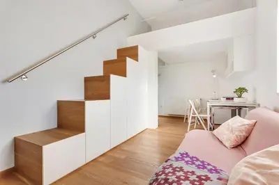 a living room with a staircase and a pink couch at Modern studio apartment in the heart of old city in Ljubljana