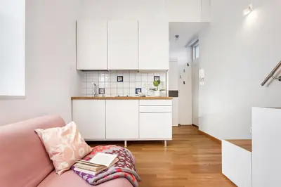 a living room with a pink couch with books on it at Modern studio apartment in the heart of old city in Ljubljana