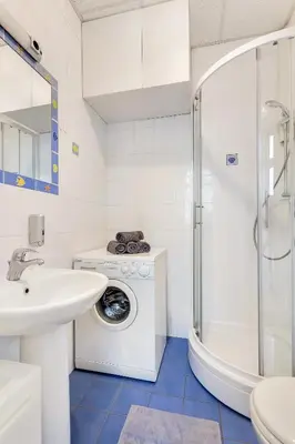 a white bathroom with a washing machine and a sink at Modern studio apartment in the heart of old city in Ljubljana