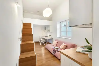 a living room with a pink couch and a staircase at Modern studio apartment in the heart of old city in Ljubljana