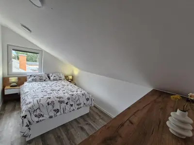 a white bedroom with a bed and a window at Livada in Ljubljana