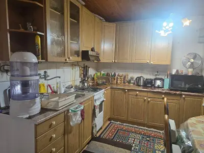 a kitchen with wooden cabinets and a stove top oven at Ofta International guests house in Senovo