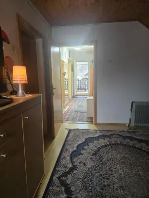 a living room with a rug and a lamp and a hallway at Ofta International guests house in Senovo