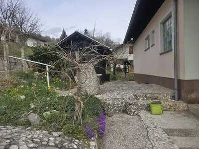 a garden with a tree and a house at Ofta International guests house in Senovo