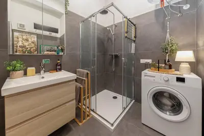 a bathroom with a washing machine and a shower at Casa1895, Stylish Old Town Apartment near Beer Fountain in Žalec