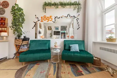 a living room with green couches and a mirror at Casa1895, Stylish Old Town Apartment near Beer Fountain in Žalec