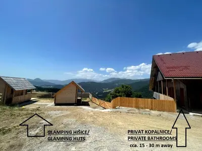 a group of buildings with mountains in the background at Scenic Glamping Huts with Mountain Views near Ljubno ob Savinji, Slovenia in Mozirska Koča