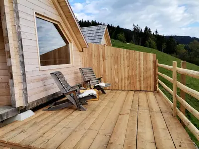 a wooden deck with a bench and a fence at Scenic Glamping Huts with Mountain Views near Ljubno ob Savinji, Slovenia in Mozirska Koča