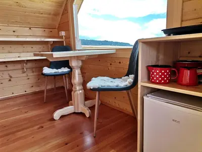 a tiny house with a table and two chairs at Scenic Glamping Huts with Mountain Views near Ljubno ob Savinji, Slovenia in Mozirska Koča
