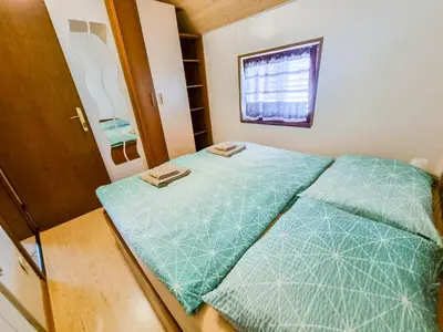 a small bedroom with a green bed with two pillows at Apartma Jakob 2 in Bovec