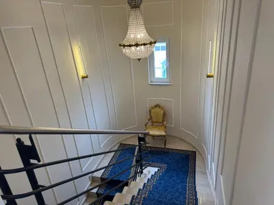 a staircase with a chandelier and a blue rug at Apartma Tyrseva in Maribor
