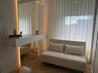 a living room with a white couch and a mirror at Apartma Tyrseva in Maribor