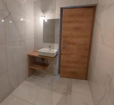 a bathroom with a sink and a wooden door at Apartma 47 in Kobarid