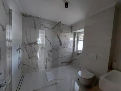 a bathroom with a toilet and a marble wall at Apartma 47 in Kobarid