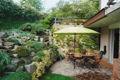 a patio with a table with an umbrella in a garden at Peaceful Heartwarming Home With A Green Terrace in Maribor