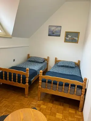 two twin beds in a room with a table at Mirni kotiček in Čatež ob Savi