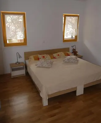 a bedroom with a large bed with two windows at Apartment House Cviter in Bovec