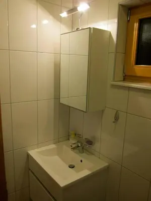a white bathroom with a sink and a mirror at Apartment House Cviter in Bovec
