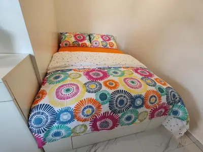 a small bed in a small room with a colorful comforter at Studio Hathor - Bikers Welcome in Kranj