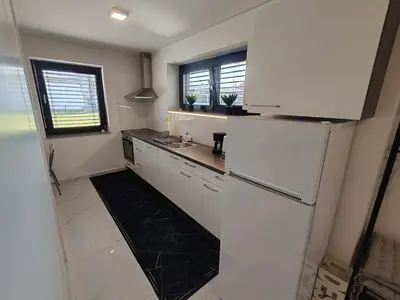 a kitchen with white cabinets and a refrigerator at Studio Hathor - Bikers Welcome in Kranj