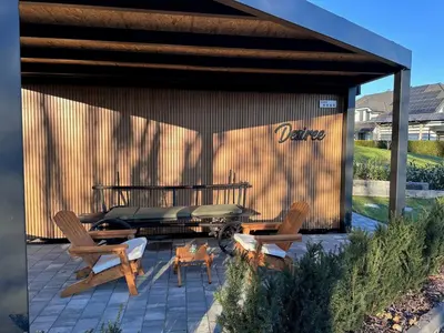 a covered patio with two chairs and a table at DESIREE with Sauna&HotTube at Potatoland Lux Resort in Šenčur