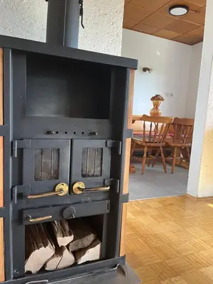 a wood stove in a living room with a table at Apartma Špan in Zgornje Gorje