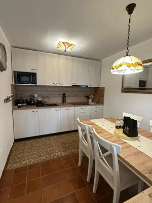 a kitchen with a wooden table and white cabinets at Bella Mura Nature Apartment Lipa 109 in Podčetrtek