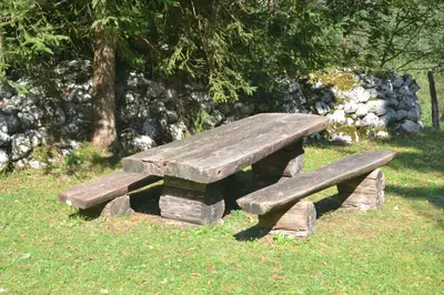 a wooden bench sitting in the grass in a park at House Pod Lipo in Trenta