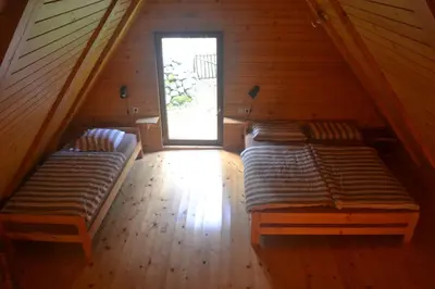 two beds in a wooden room with a window at House Pod Lipo in Trenta