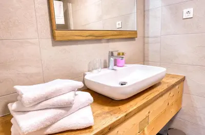 a bathroom with a sink and towels on a wooden counter at Domačija Kveder in Cerklje na Gorenjskem