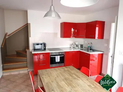 a kitchen with red cabinets and a table with a microwave at Apartment Wild Soca No 7 in Bovec