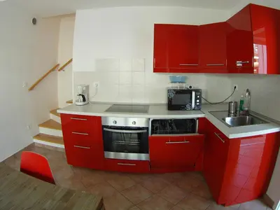 a small kitchen with red cabinets and a sink at Apartment Wild Soca No 7 in Bovec
