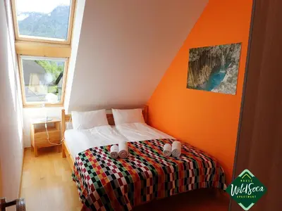 a bedroom with a bed with an orange wall at Apartment Wild Soca No 7 in Bovec