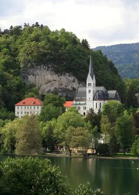 a large white church with a steeple on top of a lake at Old Parish House in Bled