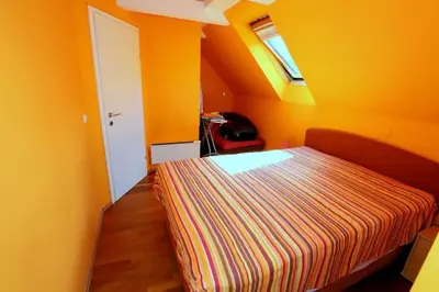 a bedroom with orange walls and a bed with a striped blanket at BledRoom in Bled