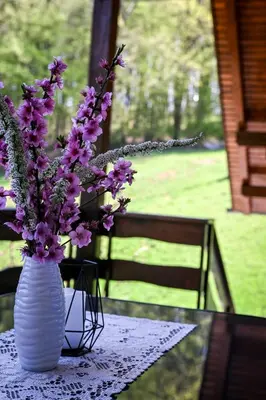 a white vase with purple flowers on a table at Countryside house in Male Brusnice