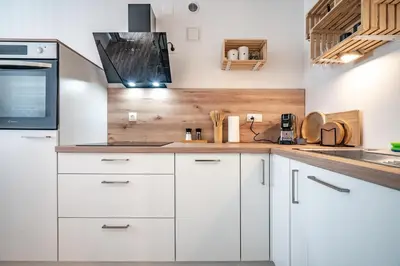 a kitchen with white cabinets and a stove at Apartma med krošnjami in Bohinj