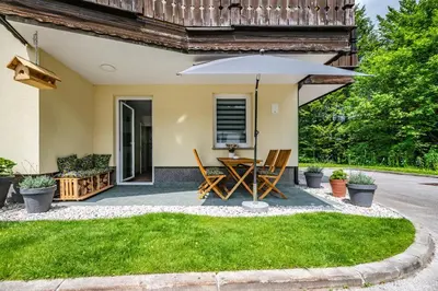a patio with a table and an umbrella at Apartma med krošnjami in Bohinj