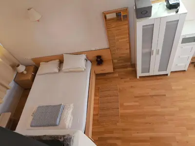 a small bedroom with a white bed and a wooden floor at Fresh romance by the river in Bohinj