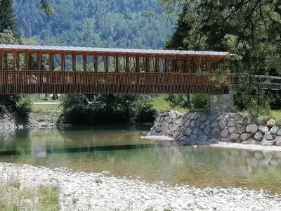 a wooden bridge over a river with a bridge at Fresh romance by the river in Bohinj