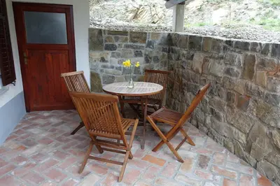a table and chairs on a patio with a stone wall at Apartment Senik in Grgar