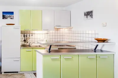a kitchen with green cabinets and a white refrigerator at Apartma Vučič in Bovec
