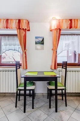 a table and chairs in a room with windows at Apartma Vučič in Bovec