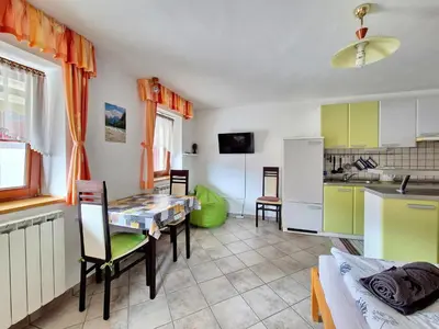 a kitchen and dining room with a table and a refrigerator at Apartma Vučič in Bovec