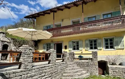 a house with a stone wall and an umbrella at Hisa Betin 4 bedroom Holiday Home in Soca Valley in Tolmin