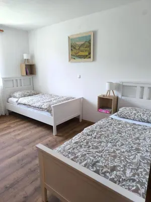 two beds in a room with white walls and wooden floors at Apartma Pri noni Silvi in Tolmin